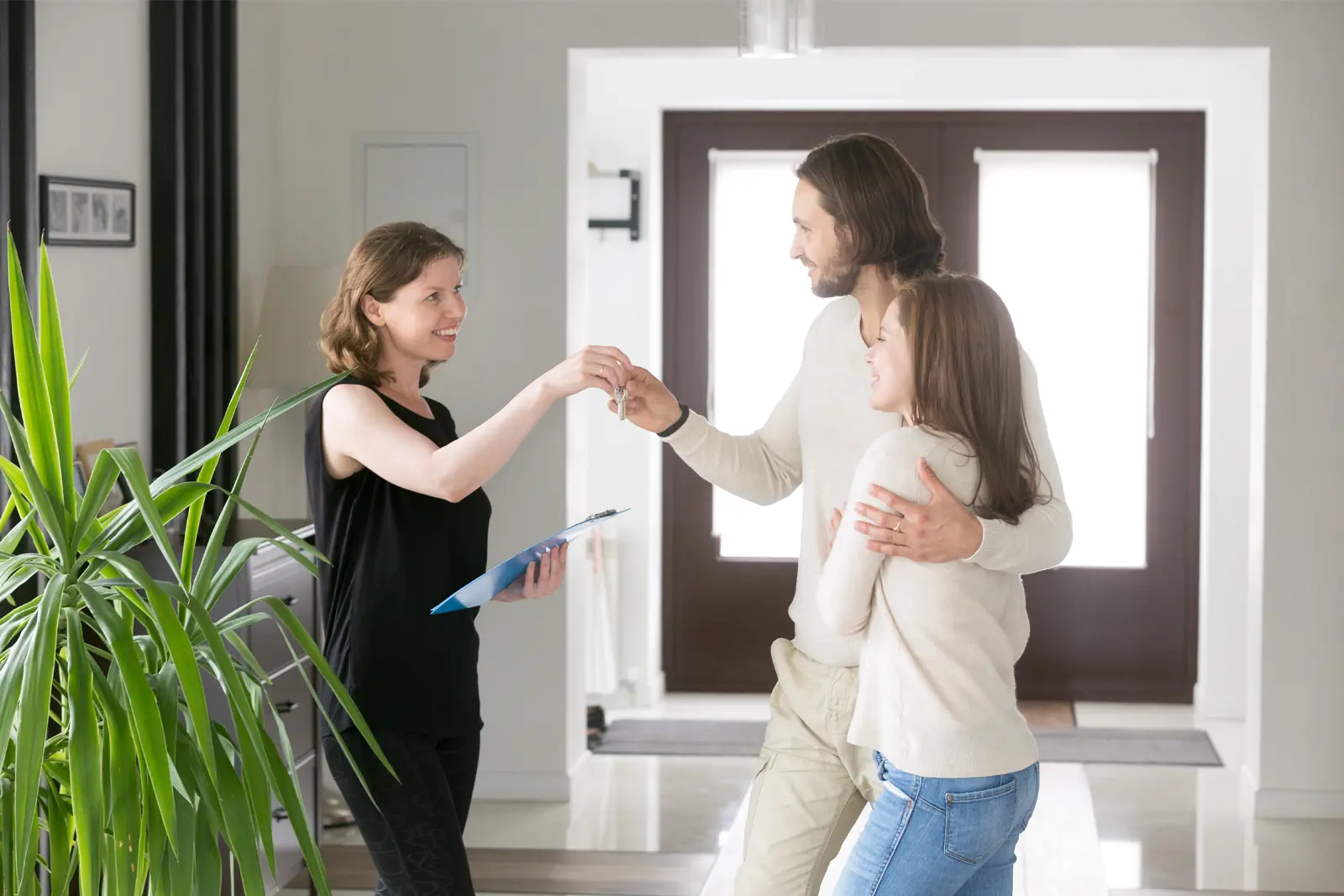 Kvinna lämnar över nycklar till par som ska hyra lägenhet i andrahand.