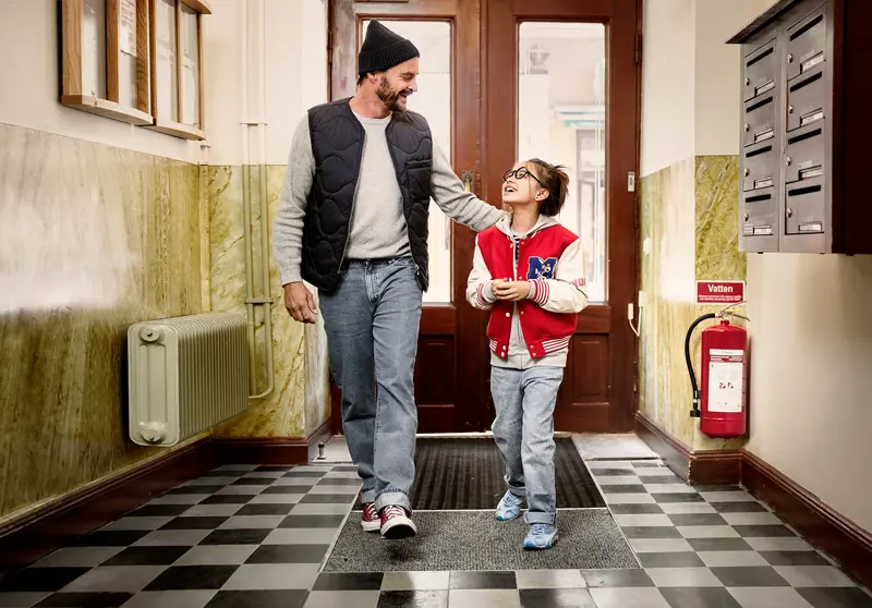 Far och dotter skrattar i entrén till en bostadsrättsförening