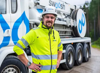 Manlig arbetare i hjälm framför Swoosh spolbil.